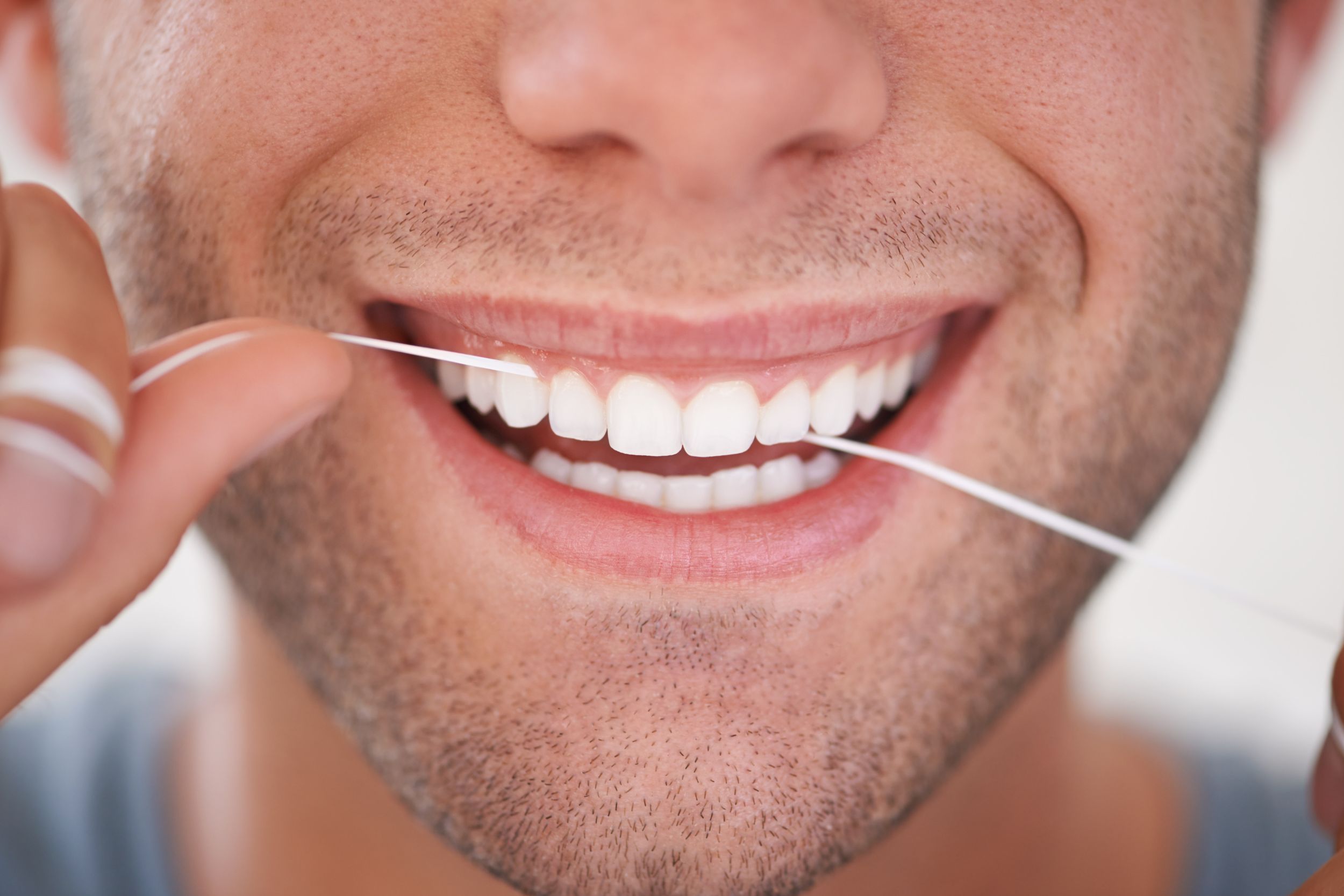 Personne qui applique un fil dentaire dans sa bouche